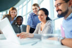 Group of business partners looking astonishingly at laptop display at meeting